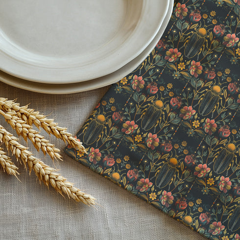Set of four dark green cloth napkins with a repeating pattern of golden beetles, coral flowers, and ochre wildflowers in an intricate botanical and entomological design.
